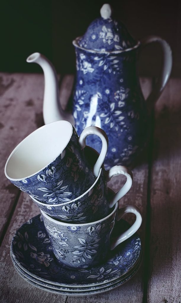 Elegant blue floral porcelain tea set with teapot and teacups on a rustic table.
